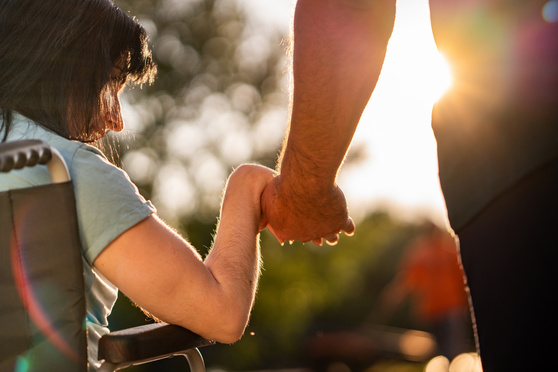 Close up women on a wheelchair holding a man's hand